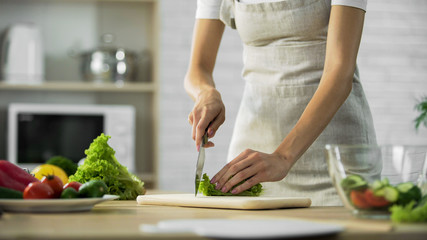 Girl chopping lettuce leaf before adding in glass bowl, healthy lifestyle, diet