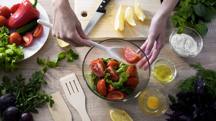 Female hand taking tomato piece with wooden spoon from glass plate, loss weight