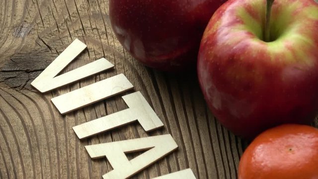 Fruit with inscription VITAMIN on brown wooden surface background