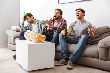 Portrait of three disappointed young men watching football