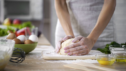Caring mother kneading the dough at the kitchen, woman making cakes, top-view