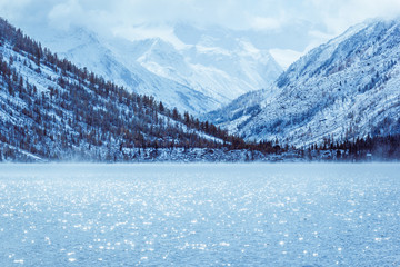 Winter lake with snow-covered pines on the Bank of the rocky mountains. The Altai mountains, fog...