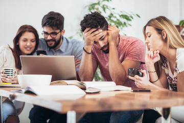 Group of multi ethnic young students preparing for exams in home interior.