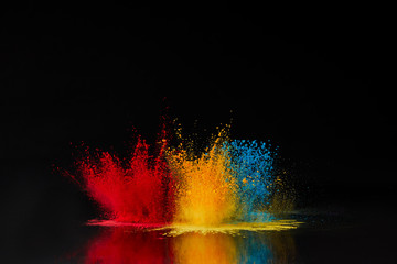 red, blue and yellow holi powder explosion on black, Hindu spring festival