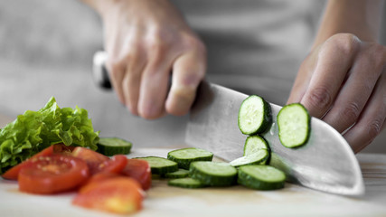Housewife hands cutting cucumber on kitchen board, vegetable salad cooking steps
