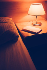Book and vintage lamp on night table in hotel room