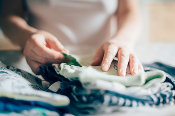 Mother sorting newborn baby clothing at home