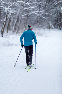 Image from back of skier athlete in forest at winter