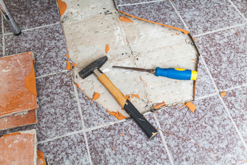 Hammer and chisel lay on floor without tiles