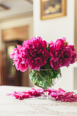 red peonies in glass vase stand on table