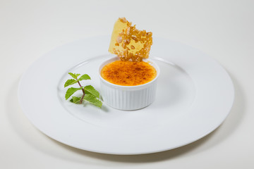 creme brulee and caramel flake on a white plate on a white background isolated