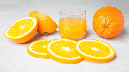 Orange juice glass with orange slices on a light wood background