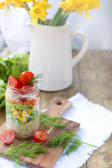 Fresh vegetable salad in a can of layers. Healthy food. Lunch at home on the table near the window. A bouquet of stars in a vase. Free space for text or a postcard.