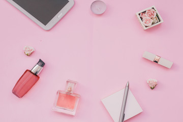Obraz na płótnie Canvas Pink background with female accessories perfume, cream, lipstick, laptop