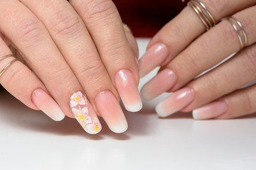 Female hands with manicure close up. Drawing of a branch with orange flowers. It is isolated on a white background.