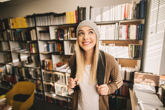 Portrait view of a gorgeous cheerful blond high school student girl standing in the school library.