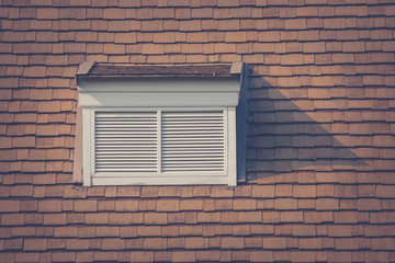 Front view of white wooden window on rooftop of wooden house in vintage style at countryside. (Selective focus)