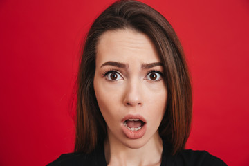 Portrait of puzzled woman 20s looking on camera with open mouth in excitement or shock, isolated...