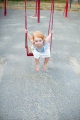 Girl in a dress on a swing on the playground