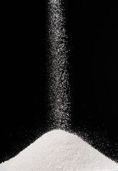 sugar falling on pile isolated on black