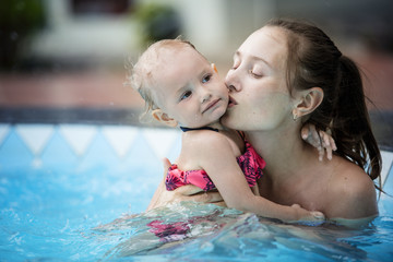 Family mother and baby girl daughter swim in the outdoor swimming pool beautiful and happy