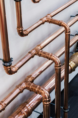 copper pipes and fittings for carrying out plumbing. Copper pipe in front of a white wall