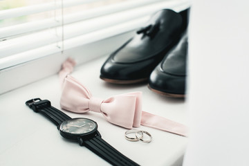 Close up of modern man accessories. beige bow tie, black leather shoes, belt and watch