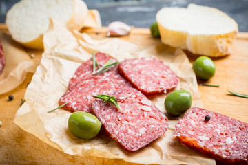 Delicious salami with olives, spices and rosemary. Selective focus.