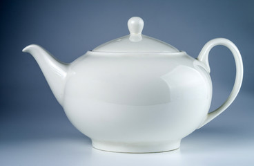 White ceramic teapot isolated on a blue background. .