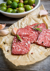 Delicious salami with olives, spices and rosemary. Selective focus.