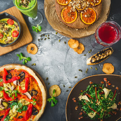 Fototapeta na wymiar Table with vegetarian food - pizza, salad, pie and drinks on dark. Flat lay, top view. Food background