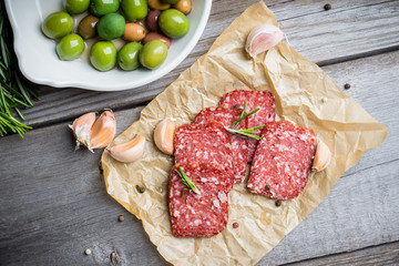 Delicious salami with olives, spices and rosemary. Selective focus.