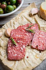 Delicious salami with olives, spices and rosemary. Selective focus.