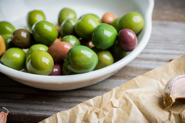 Fresh olives in white plate on the rustic background. Selective focus.