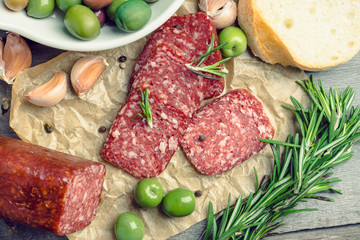 Delicious salami with olives, spices and rosemary. Selective focus.
