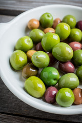 Fresh olives in white plate on the rustic background. Selective focus.