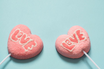 Couple lollipops pink candy on stick with Love text on pink. Funny concept. Copy space. Close up.