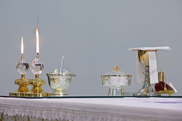two burning church candles and ostensory on the table