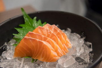 Salmon sashimi with vegetable and ice in a bowl, served in a restaurant