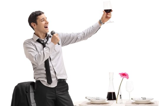 Drunk man holding a glass of wine and singing on a microphone