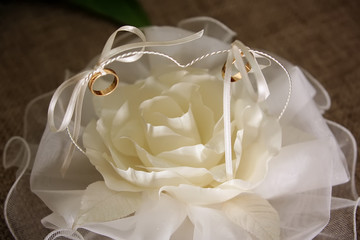 Wedding rings on white beautiful cushion in the form of a rose