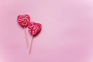 2 red candies in the form of a heart lie one above the other on a purple background