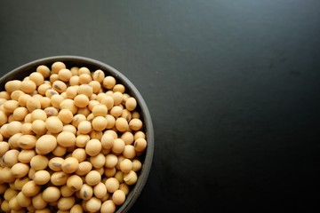 Soybeans in black bowl on black background.