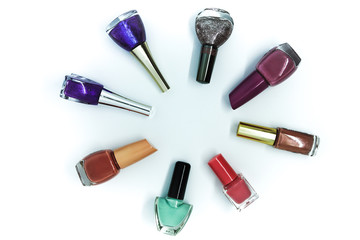 Coloured nail polish bottles stacked circle on a white background