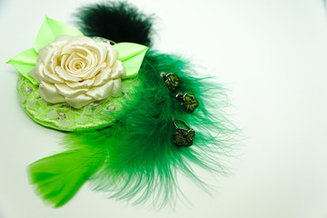 decoration on green feathers with a rose made by hands on a white background