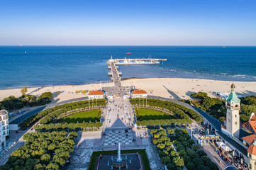 Sopot resort in Poland. SPA , old lighthouse, wooden pier (molo) with marina, yachts,  beach,  vacation infrastructure, park, promenade and walking people. Aerial view. - obrazy, fototapety, plakaty