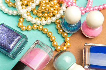 Nail Polish and pearl beads on turquoise and brown geometric background. Color trend, fashion pattern.Makeup accessories