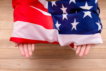 The American flag holds in his hands on a light wooden background. The Flag Of The United States Of...