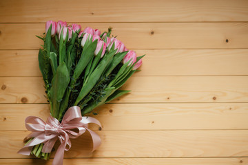 Bouquet of pink tulips and perfume with a beautiful bow on a wooden background