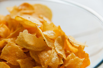  chips in a glass cup on a white wooden backdrop, harmful food